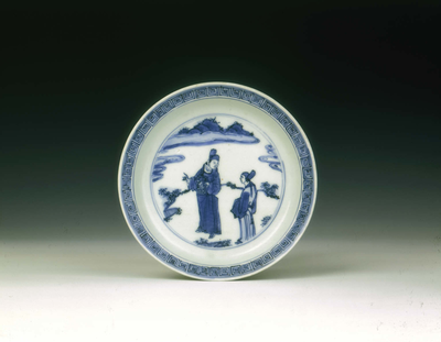A blue and white circular saucer with figures in